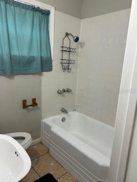 bathroom featuring baseboards, toilet, tile patterned flooring, shower / bathtub combination, and a sink