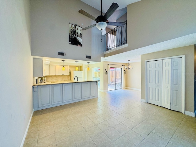 kitchen featuring ceiling fan with notable chandelier, visible vents, baseboards, hanging light fixtures, and light countertops