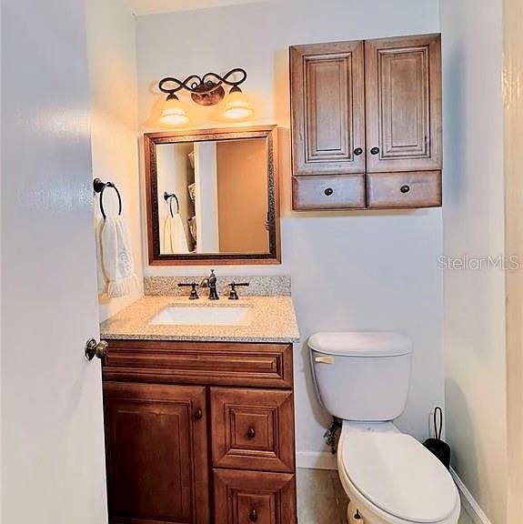 bathroom featuring toilet, vanity, and baseboards