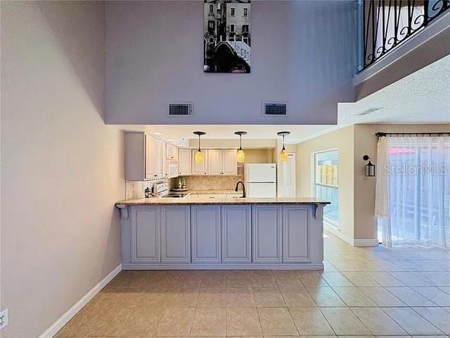 kitchen featuring a peninsula, freestanding refrigerator, light countertops, and visible vents