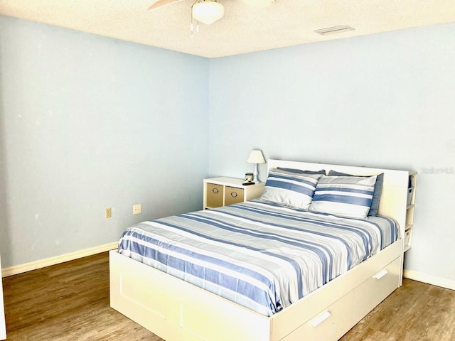 bedroom with visible vents, baseboards, and wood finished floors