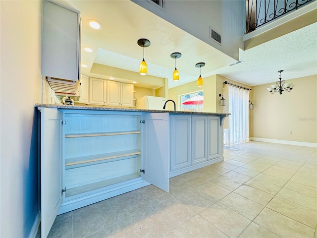 kitchen featuring visible vents, hanging light fixtures, a peninsula, and light stone countertops