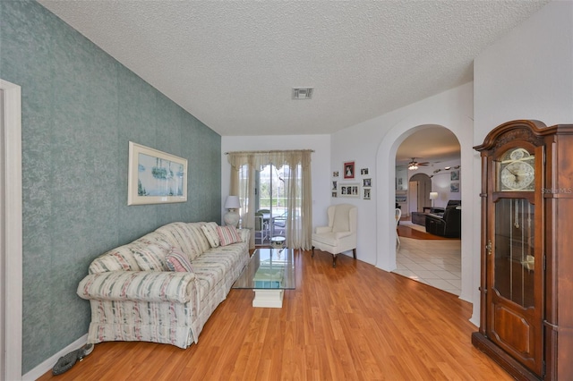 living room with ceiling fan, light hardwood / wood-style floors, and a textured ceiling