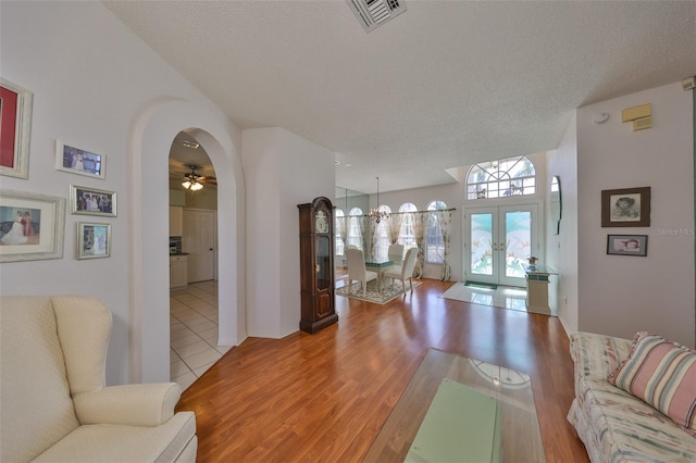 living room featuring light hardwood / wood-style flooring, a textured ceiling, and french doors