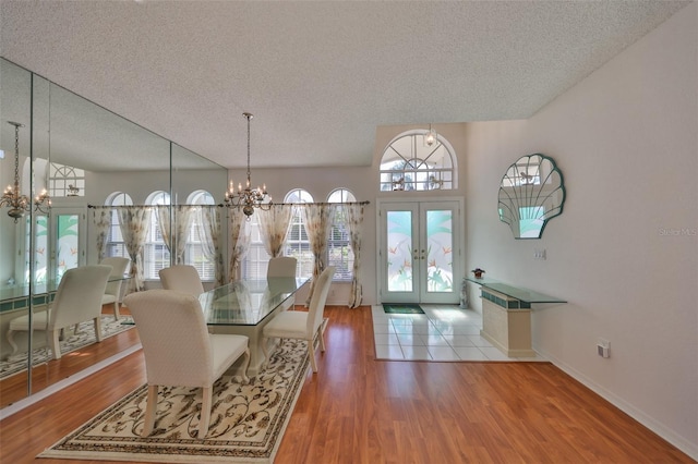 dining room featuring a notable chandelier, hardwood / wood-style flooring, french doors, and a textured ceiling