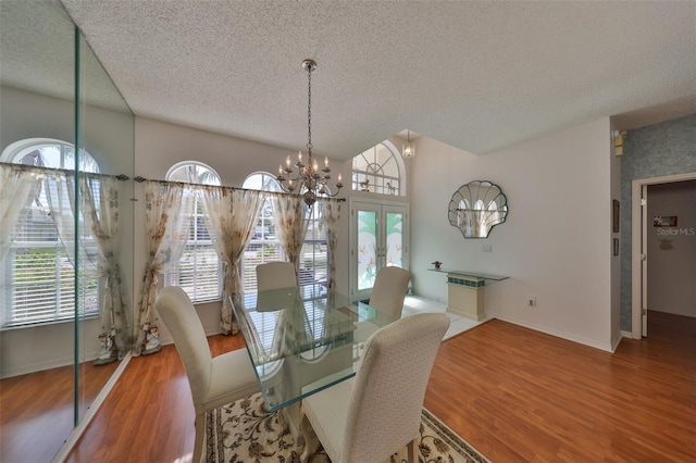 dining room with a notable chandelier, hardwood / wood-style floors, french doors, and a textured ceiling