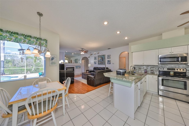 kitchen featuring sink, white cabinetry, backsplash, stainless steel appliances, and kitchen peninsula