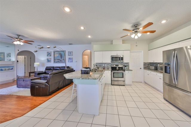 kitchen with sink, appliances with stainless steel finishes, white cabinetry, tasteful backsplash, and light tile patterned flooring