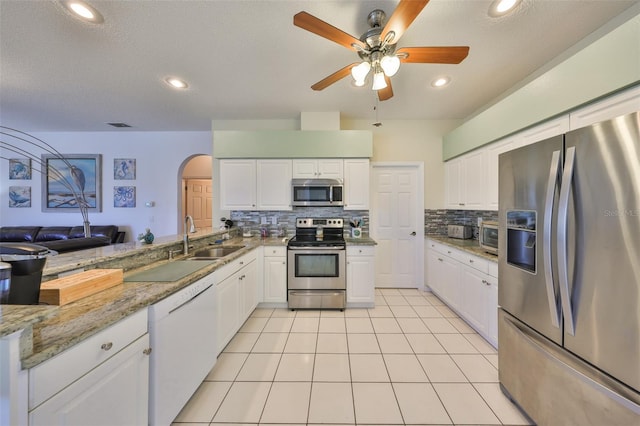 kitchen featuring light tile patterned floors, appliances with stainless steel finishes, backsplash, light stone counters, and white cabinets