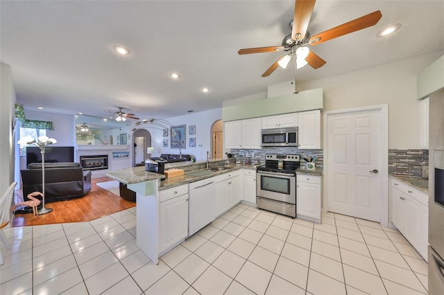 kitchen featuring appliances with stainless steel finishes, a breakfast bar area, white cabinets, light tile patterned floors, and kitchen peninsula