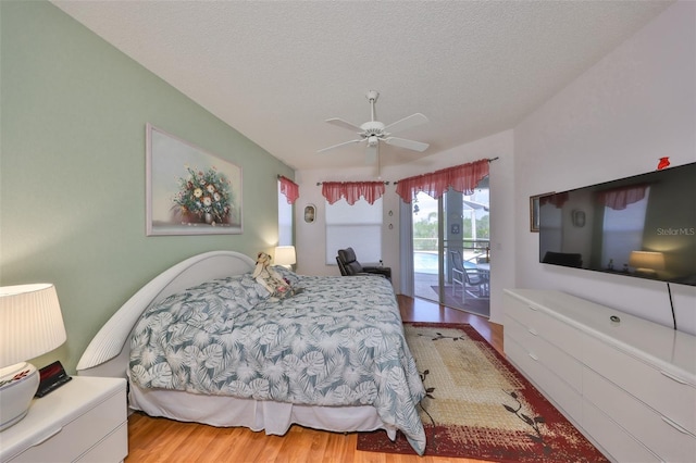 bedroom featuring ceiling fan, light wood-type flooring, a textured ceiling, and access to outside