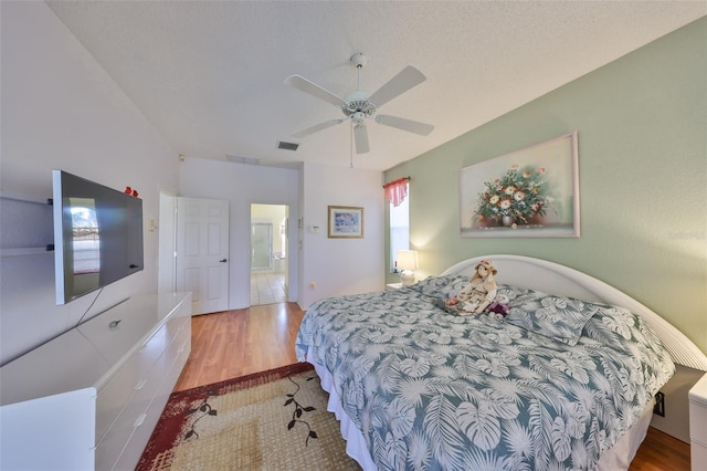 bedroom featuring ceiling fan, light hardwood / wood-style flooring, and a textured ceiling