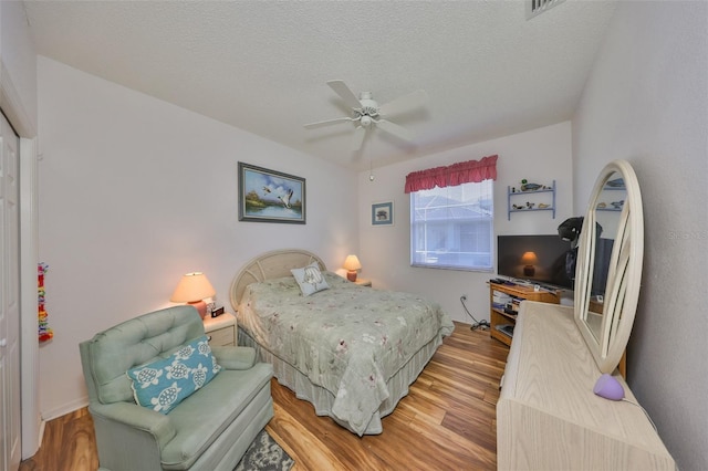 bedroom with ceiling fan, a textured ceiling, and light wood-type flooring