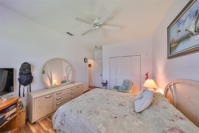 bedroom with ceiling fan, a closet, light hardwood / wood-style flooring, and a textured ceiling