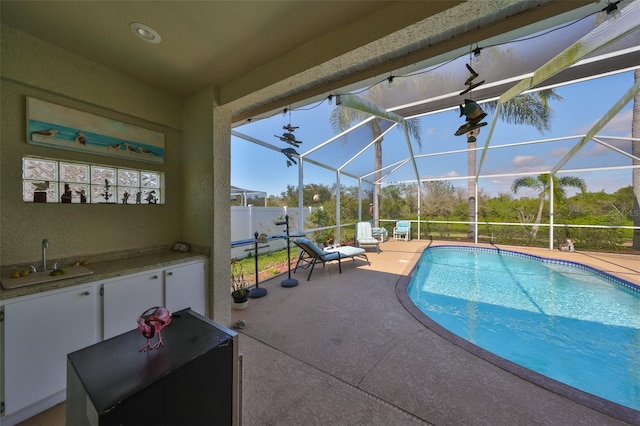 view of swimming pool featuring a patio, sink, and glass enclosure