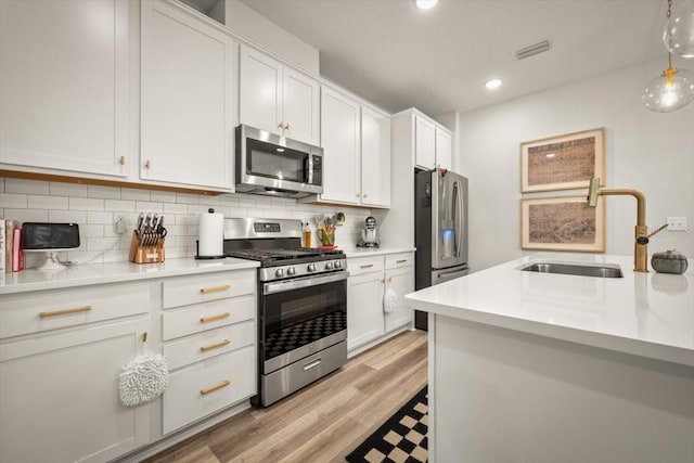 kitchen with sink, hanging light fixtures, white cabinets, stainless steel appliances, and backsplash