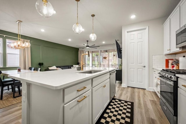 kitchen with stainless steel appliances, a kitchen island with sink, and white cabinets