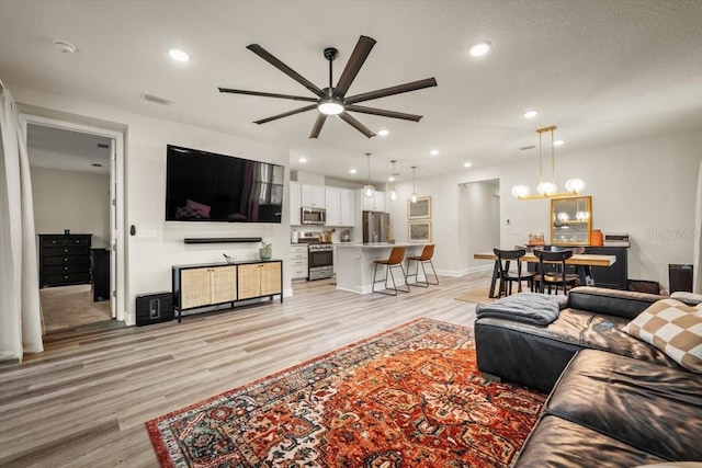 living room featuring ceiling fan and light hardwood / wood-style flooring