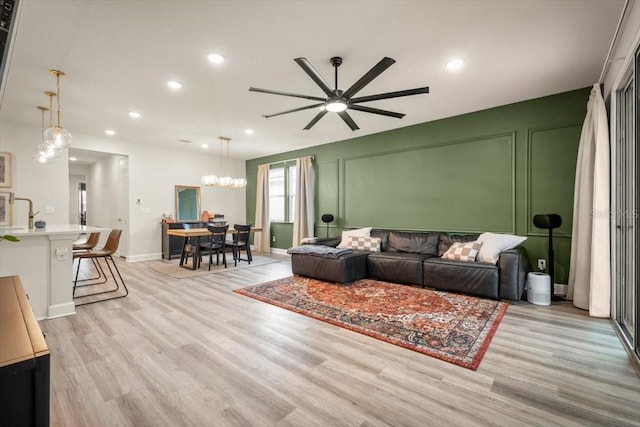 living room with ceiling fan and light hardwood / wood-style flooring