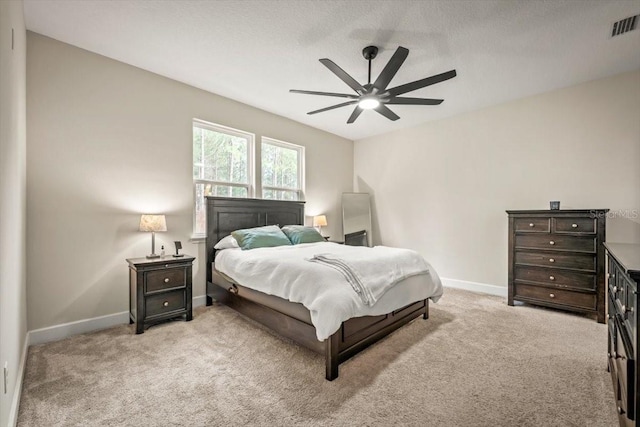 bedroom featuring a textured ceiling, light colored carpet, and ceiling fan