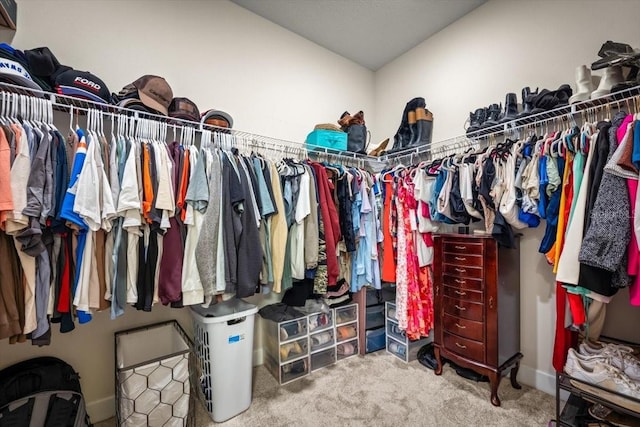 walk in closet with vaulted ceiling and carpet flooring