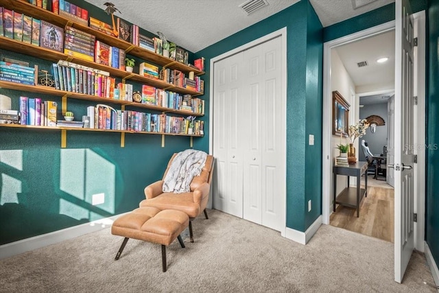 sitting room with light carpet and a textured ceiling