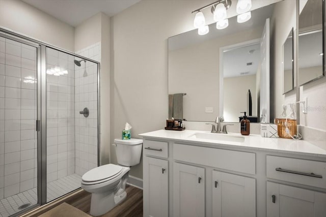 bathroom with vanity, hardwood / wood-style floors, a shower with shower door, and toilet