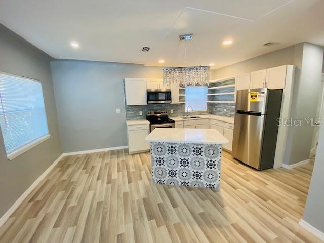 1829 10th St N, Saint Petersburg, FL 33704 - kitchen with sink, pendant lighting, stainless steel appliances, decorative backsplash, and white cabinets