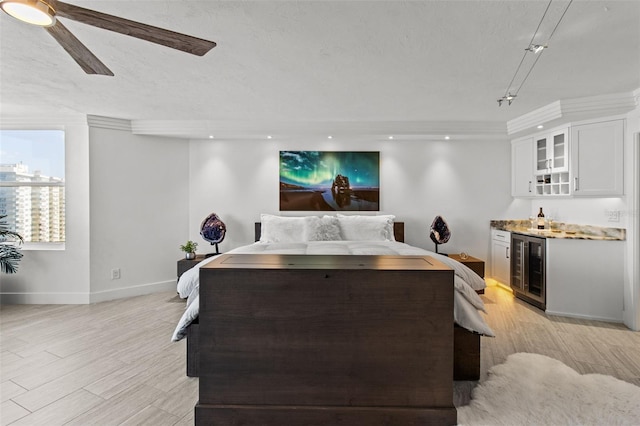 bedroom featuring ceiling fan, bar, wine cooler, a textured ceiling, and light wood-type flooring