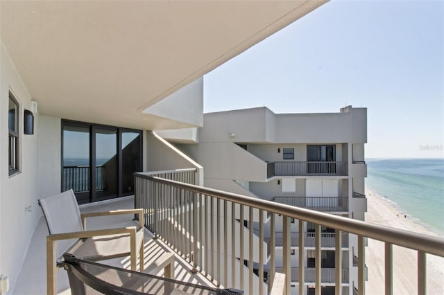 balcony with a water view and a view of the beach