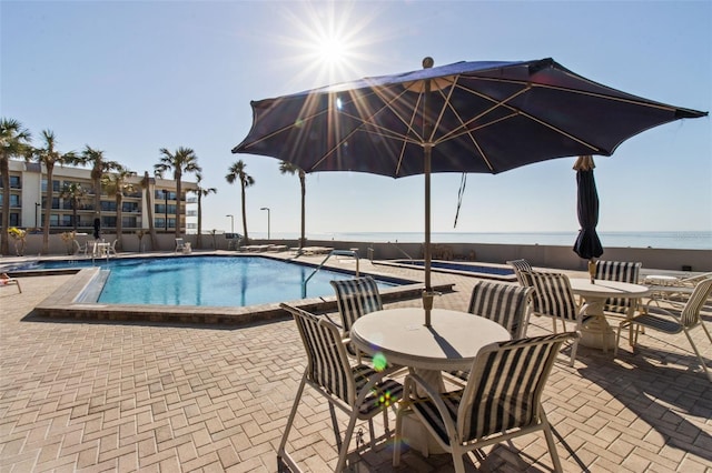 view of swimming pool featuring a patio and a water view