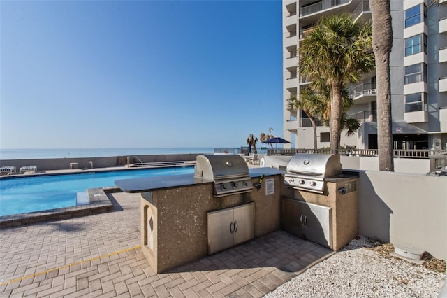 view of patio / terrace featuring area for grilling, a water view, and exterior kitchen