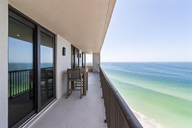 balcony featuring a water view and a beach view