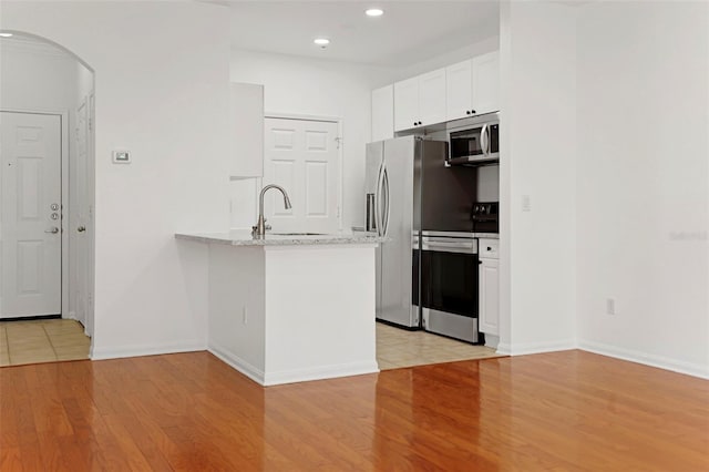 kitchen with sink, light stone counters, stainless steel appliances, light hardwood / wood-style floors, and white cabinets