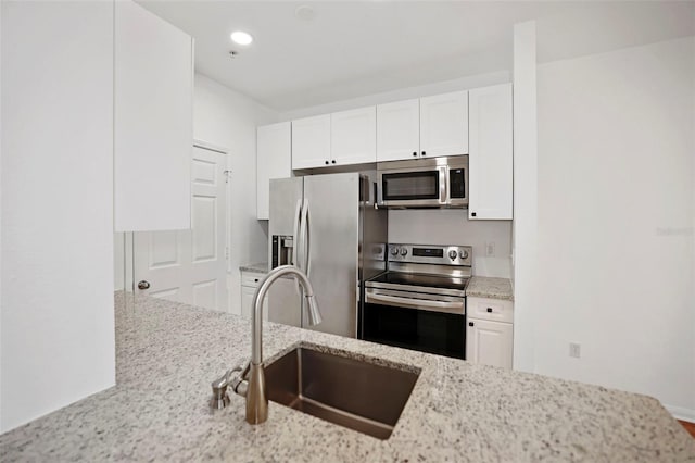 kitchen featuring white cabinetry, sink, stainless steel appliances, and light stone countertops