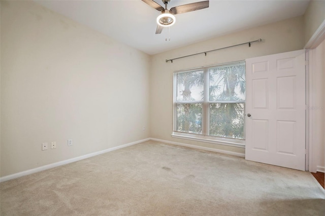 empty room featuring ceiling fan and light colored carpet