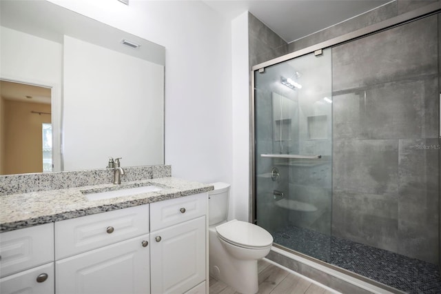 bathroom featuring walk in shower, wood-type flooring, vanity, and toilet