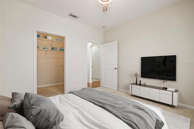 bedroom with light carpet and a walk in closet