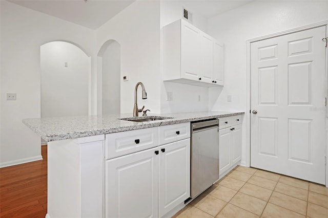 kitchen featuring sink, white cabinetry, light stone counters, stainless steel dishwasher, and kitchen peninsula