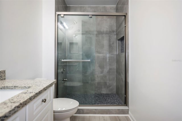 bathroom featuring vanity, toilet, a shower with door, and hardwood / wood-style floors