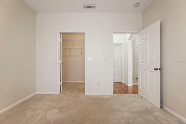 unfurnished bedroom featuring light colored carpet, a spacious closet, and a closet