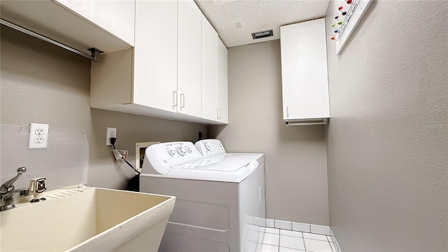 laundry room featuring cabinets, sink, a textured ceiling, and washer and clothes dryer