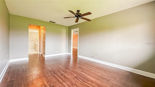 empty room with ceiling fan, wood-type flooring, and a textured ceiling