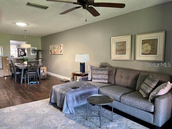 living room featuring ceiling fan, hardwood / wood-style floors, and a textured ceiling