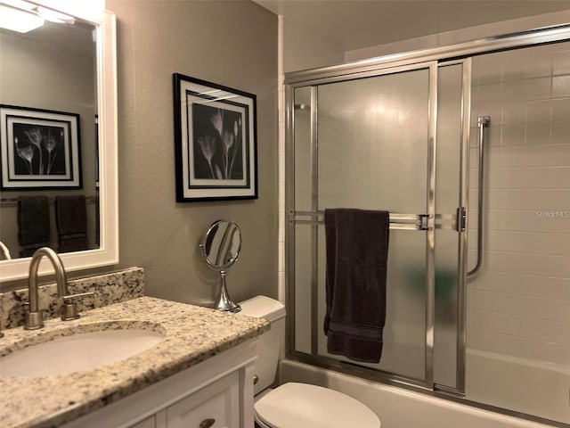 full bathroom with enclosed tub / shower combo, vanity, and toilet