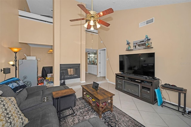 living room featuring a multi sided fireplace, high vaulted ceiling, light tile patterned floors, and ceiling fan