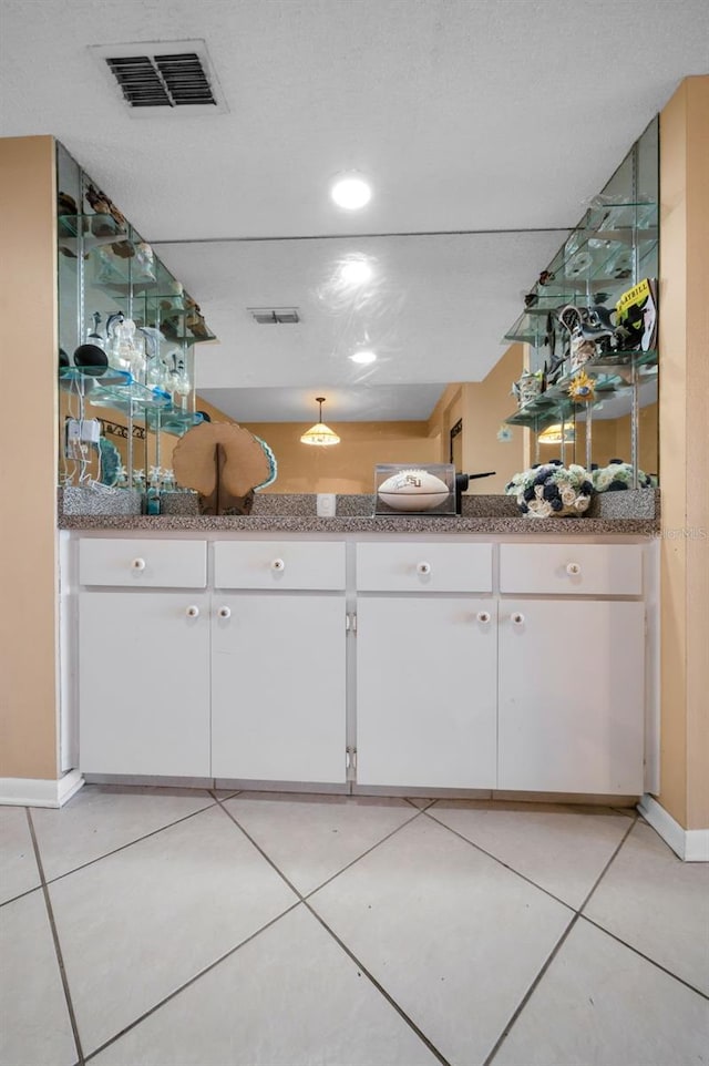 interior space featuring white cabinetry, stone countertops, and light tile patterned flooring