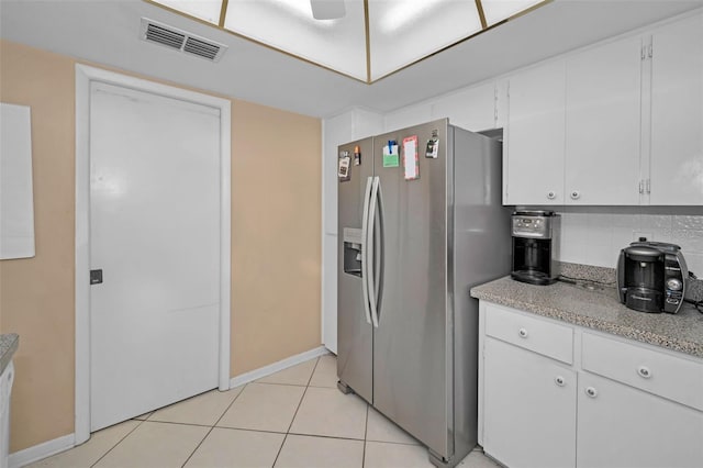 kitchen featuring light tile patterned flooring, stainless steel fridge, decorative backsplash, and white cabinets