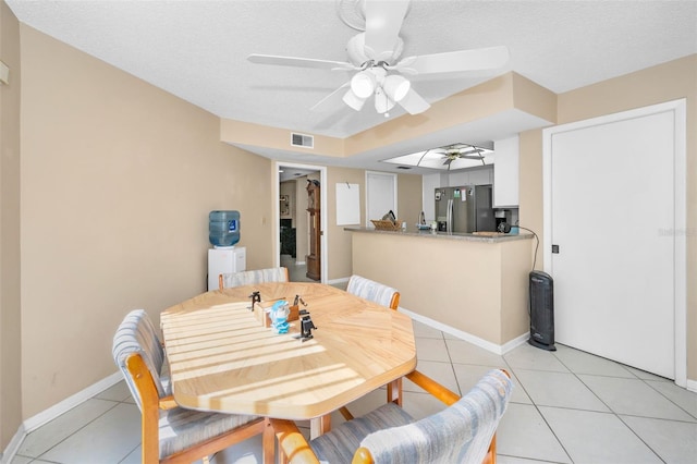 dining space with light tile patterned flooring, ceiling fan, and a textured ceiling