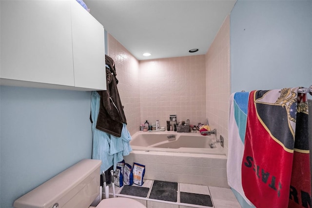 bathroom featuring tile patterned flooring, sink, tiled bath, and toilet